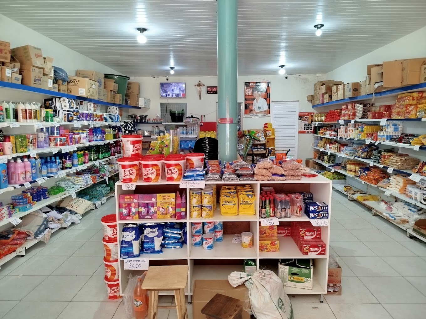 Interior da mercearia com prateleiras de não perecíveis e produtos de limpeza